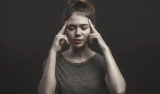 photo of a women with her eyes closed and her fingers at her temples