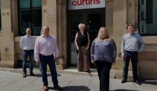 Staff members stood outside a building with a sign Curtins on the front