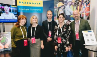 Photo of Cristin, Simon, Ewan, Hannah and Emily on front of their promotional stand at the employee ownership association conference