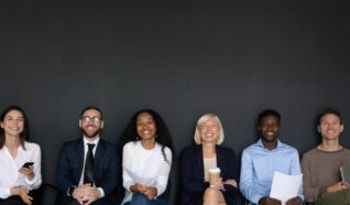 a group of men and women all sat in a row behind a black background