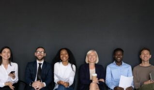 a group of men and women all sat in a row behind a black background