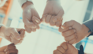 Group of people stood in a circle with the fists together