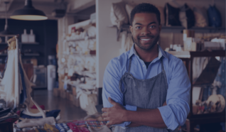 man in an apron stood in front their business