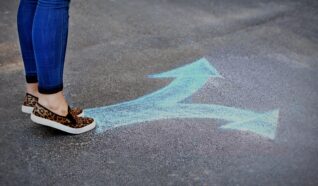 persons stood on tip toes behind an arrow pointing 2 ways