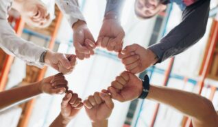 Group of people stood in a circle with the fists together