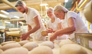 3 people in uniform working in a bakery